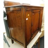 An early 20thC oak cupboard, with a raised back and a single hinged door, with a decorative