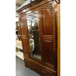 A late Victorian walnut wardrobe, with a single bevelled glass door, above a drawer, 197cm high,