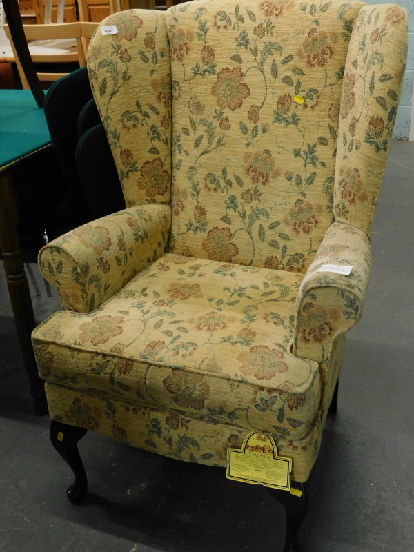 A Sherborne wing back armchair, in floral fabric on cabriole legs. The upholstery in this lot does