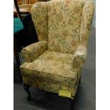 A Sherborne wing back armchair, in floral fabric on cabriole legs. The upholstery in this lot does