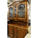 An oak dresser, the top with two leaded glazed doors, the base with two hinged doors.