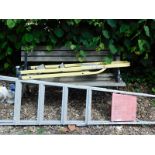A slat back garden bench with metal ends, and two step ladders.