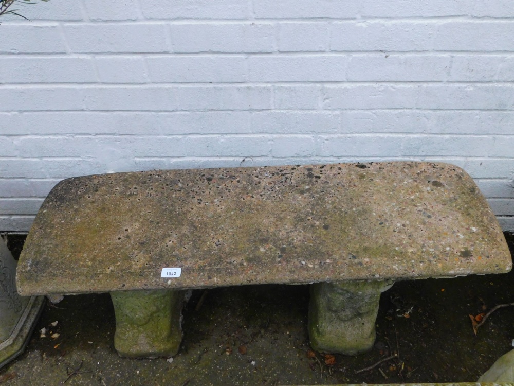 A reconstituted stone garden bench, the oblong top raised on two shaped supports 38cm high, 92cm wid