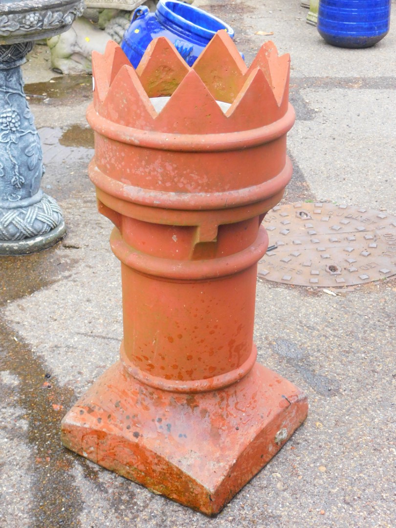 A fire clay chimney pot with castellated top on a plain cylindrical stem and square base 280cm high.