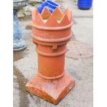 A fire clay chimney pot with castellated top on a plain cylindrical stem and square base 280cm high.