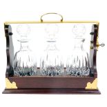 A Waterford crystal three bottle tantalus, decorated in the Lismore pattern, within a mahogany and b