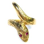 A 9ct gold snake ring, the ring head formed as head and tail of the snake set with two garnet eyes,