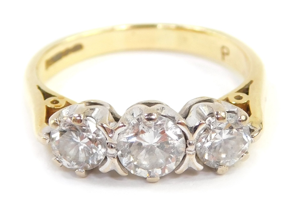 An 18ct gold three stone diamond ring, the central round brilliant cut stone in four claw setting, 4