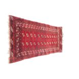 A Tekke red ground rug, decorated with guls and geometric motifs, 216cm x 107cm.