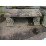 A reconsituted stone garden bench, the rectangular top raised on two lion supports on molded border