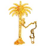 A palm tree and monkey brooch, the palm tree with a figure climbing with applied decoration, on sing