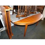 An oval teak extending dining table, with two leaves.
