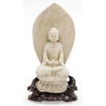 An 18thC Chinese carved stone figure of a man sat in the Lotus position holding a cup, on a carved o