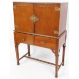 A 1950s/60s stained oak cocktail cabinet, the top Eastern inspired with applied brass mounts, openin