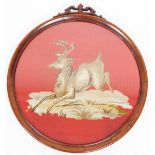 An early 20thC mahogany framed circular tapestry of a deer, on a red ground, 40cm diameter.