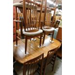 A teak extending dining table and a set of six matching chairs, the top with rounded corners,