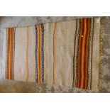 A wool cut rug, on a cream ground with orange borders and tassel ends, 163cm x 86cm.