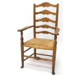 An early 19thC ash and elm country made ladder back chair, with shaped arms, and a rush seat on turn