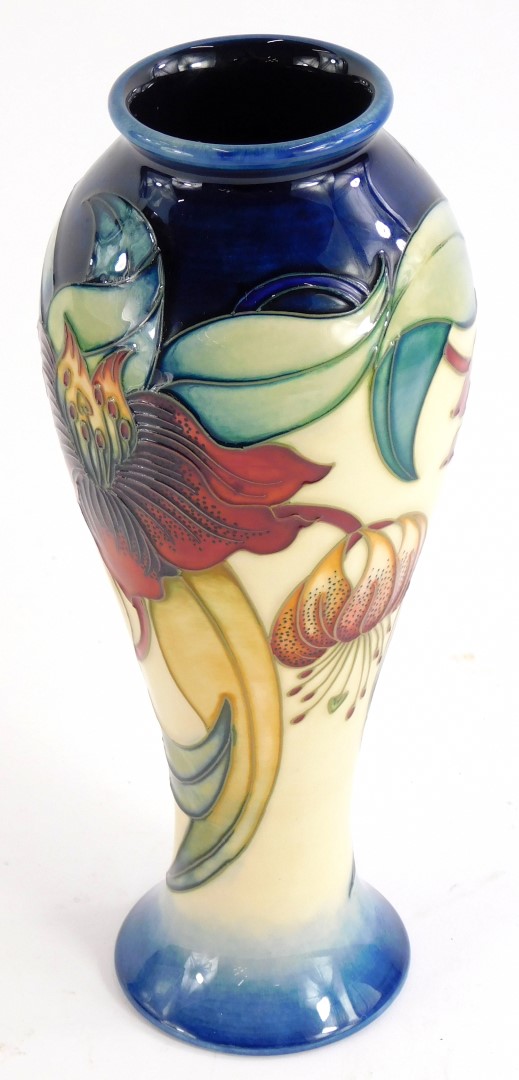 A Moorcroft baluster shaped vase, with tube line decoration of flowers, in red and cream within navy