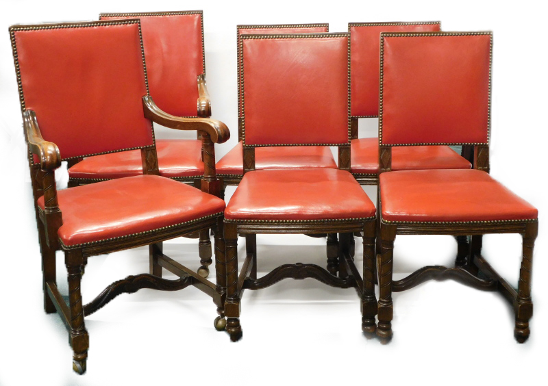 A set of six oak dining chairs, each with a red leather padded back and seat, with brass studded bor