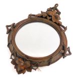 A late 19th/early 20thC Black Forest carved wall mirror, the frame decorated with leaves and berries