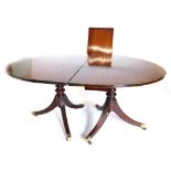 A mahogany extending dining table in Regency style, the top with a reeded edge, on two turned pillar