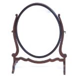 A mahogany dressing mirror, with oval plate and shaped frame, 47cm wide.