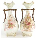 A pair of Moore and Co blush ivory ceramic vases, each decorated with flowers, 27cm high.