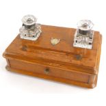 A late 19th/early 20thC inkstand, with a drawer and two cut glass wells, a presentation shield shape