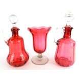 Two similar Victorian cranberry tinted claret jugs and stoppers, and a cranberry tinted celery vase.