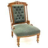 A Victorian oak nursing chair, with a carved show frame, upholstered in green fabric on turned legs