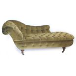 A Victorian walnut chaise lounge, upholstered in buttoned green fabric, on turned legs with ceramic