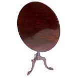 A mahogany tilt top table in George III style, the circular top on a turned part fluted column, on l