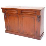 A Victorian mahogany side cabinet, with two frieze drawers above two arched panel doors on a plinth,