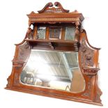 A late Victorian 20thC walnut overmantel mirror, with a swan neck pediment, above a carved frieze, a