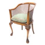 An early 20thC walnut tub shaped chair, with a tub shaped bergere chair, with a caned back on leaf c