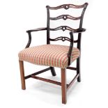 A mahogany open armchair in George III style, with a pierced carved ladder back, shaped arms and a p