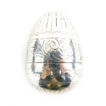 A white metal egg shaped nutmeg grater, decorated with scrolls, leaves and line decoration, 4cm high