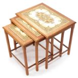 A nest of three teak tables, each with a tiled top and chamfered legs, the largest 55cm wide.