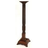 A mahogany torchere or plant stand, with a circular dished top on a part reeded turned leaf and whea