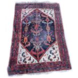 A Persian rug, with a central lozenge shaped medallion, decorated with leaves, flowers, etc., on a b