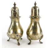 A pair of Edwardian silver pepper pots, of baluster form, the lids each with a finial on three scrol