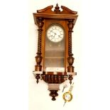 A late 19th/early 20thC Vienna wall clock, in a walnut case with a white enamel dial, 66cm long.