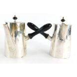 A near pair of George V silver Argylls, both with ebonised knops and handles and ram crests, one wit