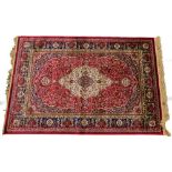 A red ground Kashmere type rug, with a design of a cream medallion, on a red ground with blue spandr