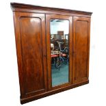 A Victorian figured mahogany triple wardrobe, with a moulded cornice above a central mirror, flanked