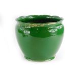 An early 20thC green glazed pottery jardiniere, picked out in gilt, (AF), 29cm diameter.