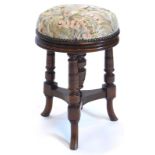 A late Victorian walnut piano stool, with a padded top on three turned supports, with splayed legs,