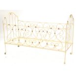 A Victorian folding wrought iron child's bed or cot, with scroll decoration, later painted in pink a