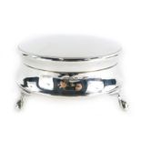 A George V silver trinket or powder box, with a plain circular hinged lid, on claw and ball feet, Bi